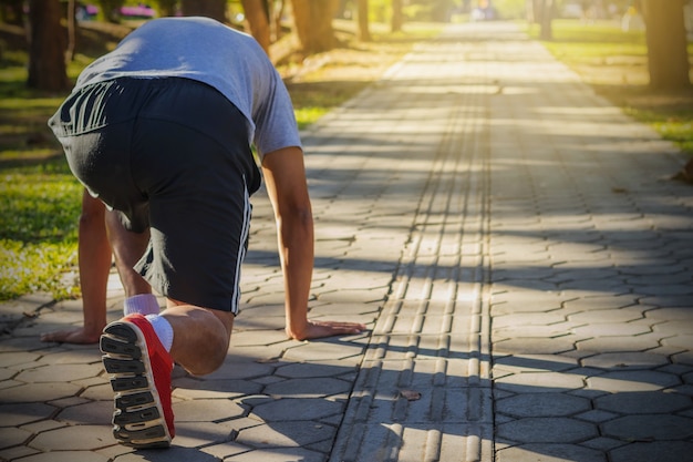 Back view of a young man in starting position for running on sports track