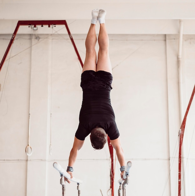 写真 平行棒でトレーニングしている若い男の背面図