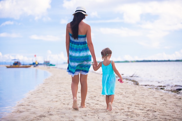 Вид сзади молодой матери и ее маленькой дочери, прогулки по морю