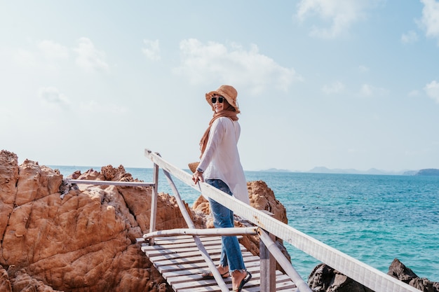 Punto di vista posteriore di giovane donna asiatica musulmana che guarda dal ponte di legno.