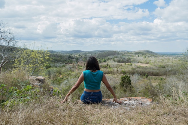 Back view of young woman looking at the horizon from the heights of the hill