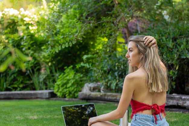 Back view of young woman looking to the side while holding her hair in natural enviroment with copy