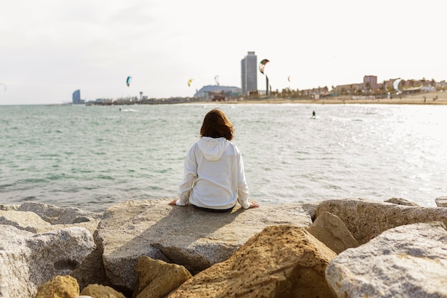 Back view of young woman resting on seafront