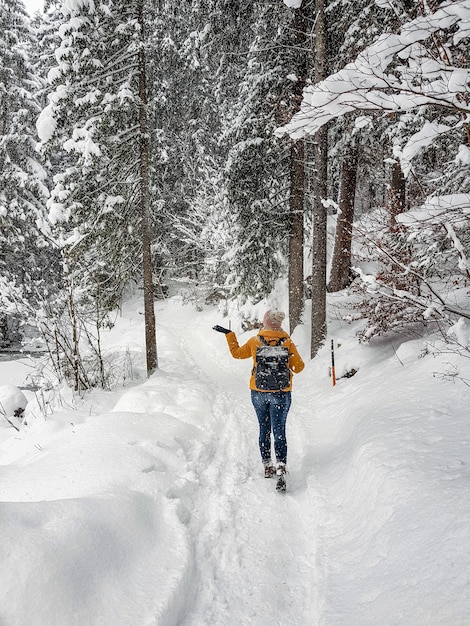 Back view of a young woman walking into the woods in Austria during winter