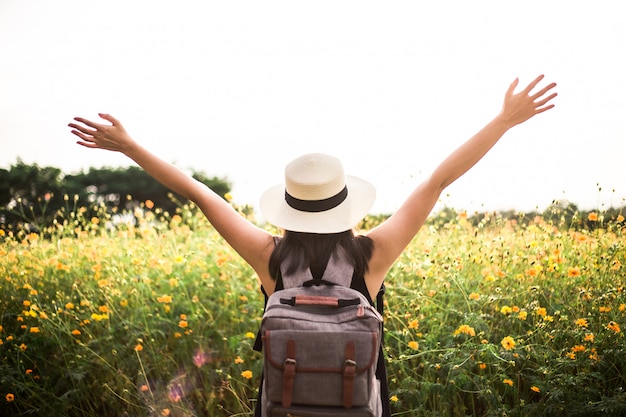 The back view of a young woman walking out on a beautiful flower field 