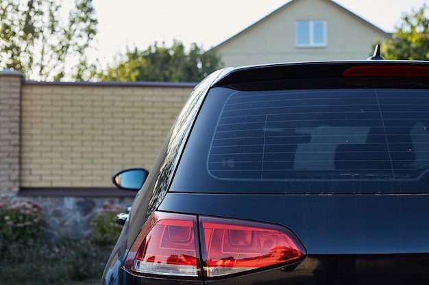 Photo back window of black car parked on the street in summer sunny day, rear view. mock-up for sticker or decals