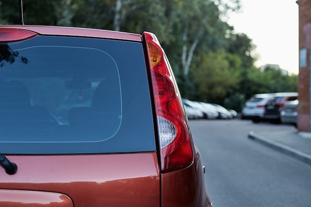 Photo back window of red car parked on the street in summer sunny day, rear view. mock-up for sticker or decals