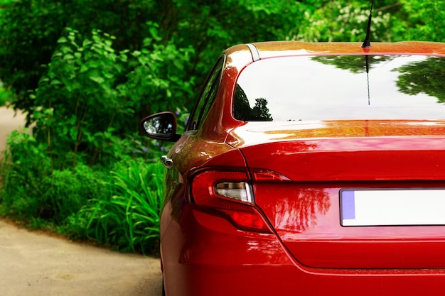 Заднее окно красной машины, припаркованной на улице в летний солнечный день, макет заднего вида