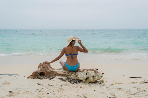 Foto retro della donna in costume da bagno seduta sul tronco di legno di playa blanca bar a cartagena in colombia