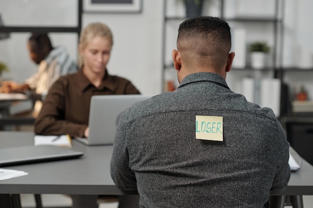 Back of young multiethnic man with word loser written on notepaper