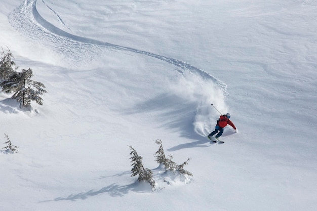 Backcountry skier glides effortlessly through the powder snow and their bright red jacket standing out against the white canvas