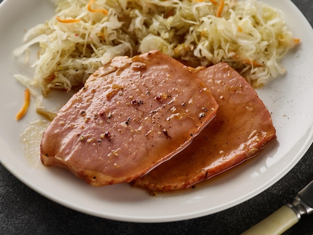 Запеченный стейк из свинины Kasseler с квашеной капустой Копченый свиной лев Нарезанная копченая свиная отбивная на деревянной доске