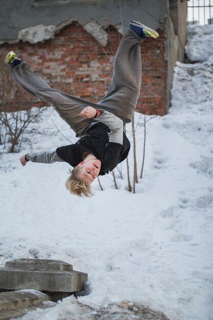 Backflip паркур в зимнем снежном парке - светловолосый подросток, вертикальный