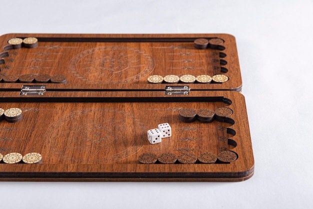 Photo backgammon game in a wooden board with rolling dices on white ground