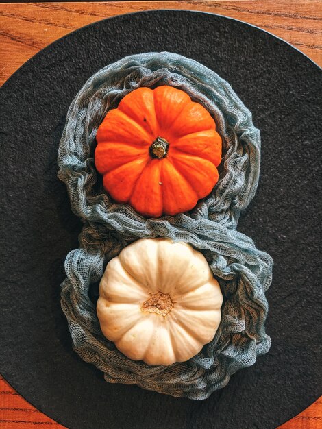 Background of autumn harvest of small orange different pumpkins on black plate close up top view
