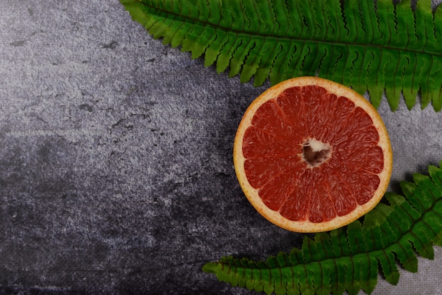 background banner with exotic fruit grapefruit and green palm leaves on dark background