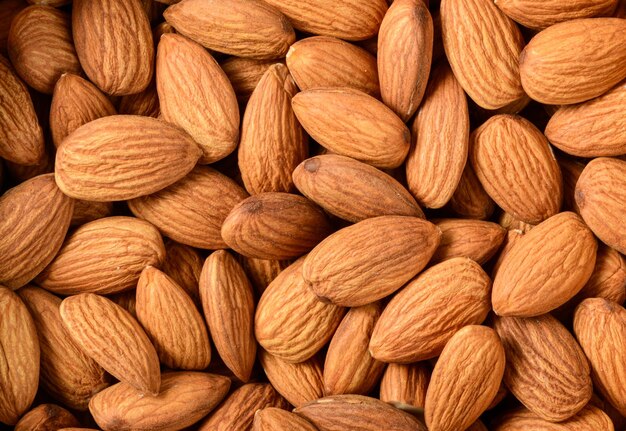 Background of big raw peeled almonds situated arbitrarily They are highly nutritious and rich in healthy fats or Highdensity lipoprotein HDL cholesterol antioxidants vitamins and minerals