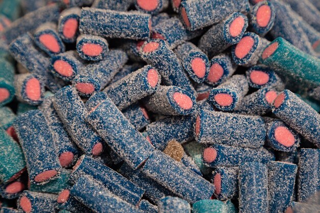 砂糖のクローズアップで覆われた青とピンクの歯ごたえのあるゼラチンお菓子の背景