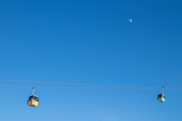 背景の青い空と月、ミニマリスト プランのケーブルカー キャビン。