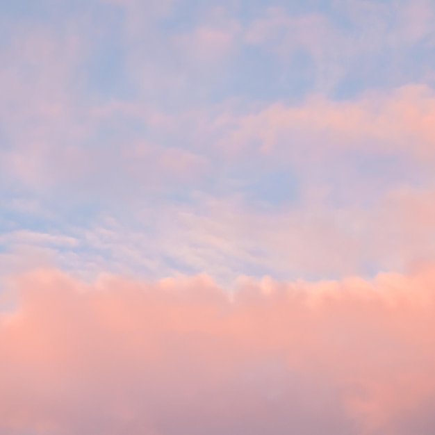 夕焼けの淡いピンクの雲と青い空の背景