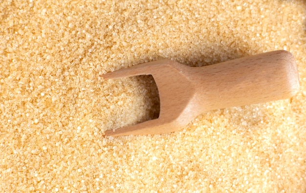 Background brown sugar heap and wooden spoon