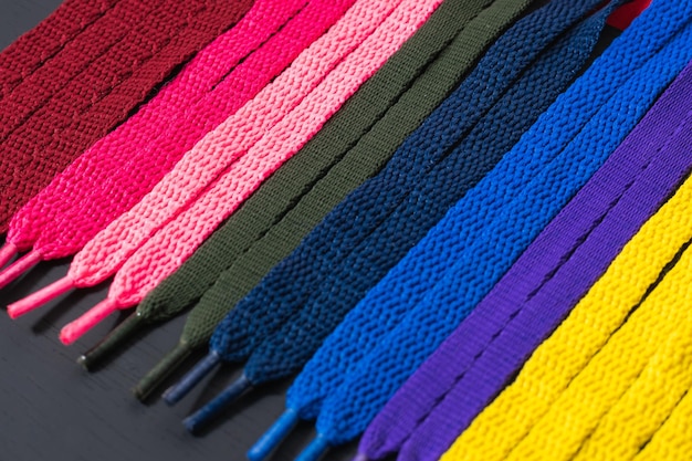 Background of colored shoelaces on black wood arranged diagonally, concept of perfection