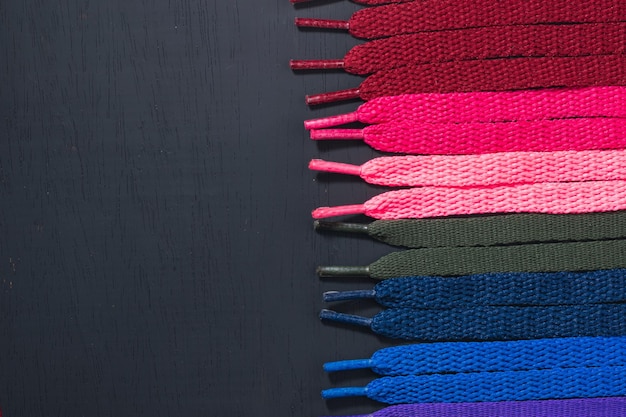 background of colored shoelaces on black wood arranged horizontally concept of perfection