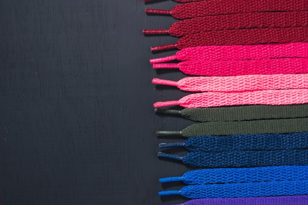 Background of colored shoelaces on black wood arranged horizontally concept of perfection