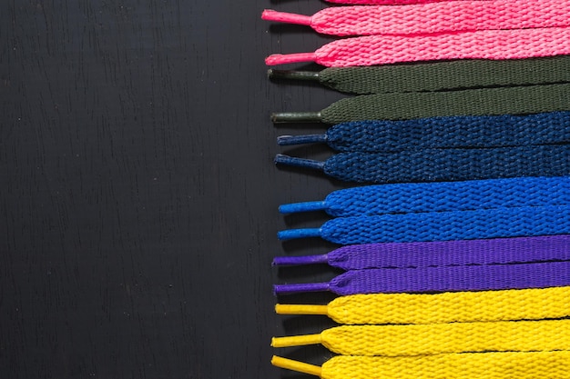 Background of colored shoelaces on black wood arranged horizontally, concept of perfection