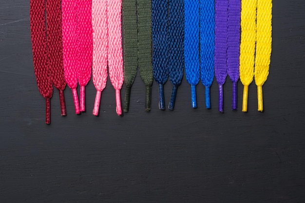 background of colored shoelaces on black wood arranged vertically concept of perfection