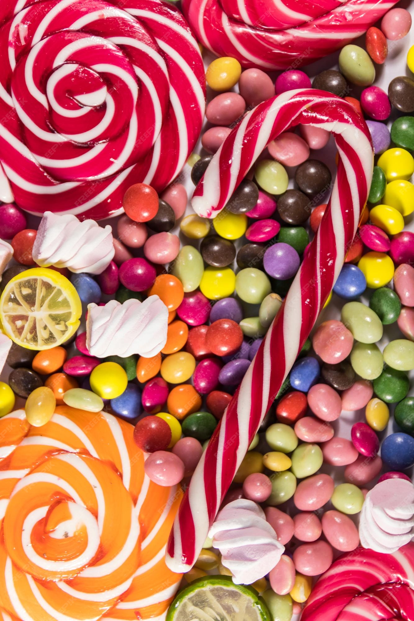Premium Photo | Background of colorful chocolate candies lollipops candy  cane and marshmallows