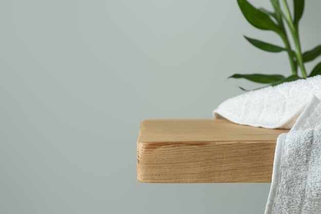 Background for cosmetics Wooden shelf with a towel and green bamboo on the background