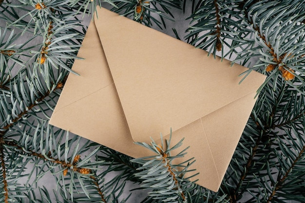 Background creative image with close up texture of fir branches with beige kraft paper envelope. Top view. Copy space