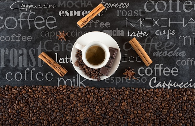 Background of cup coffee beans with cinnamon and anise on black board with chalk written