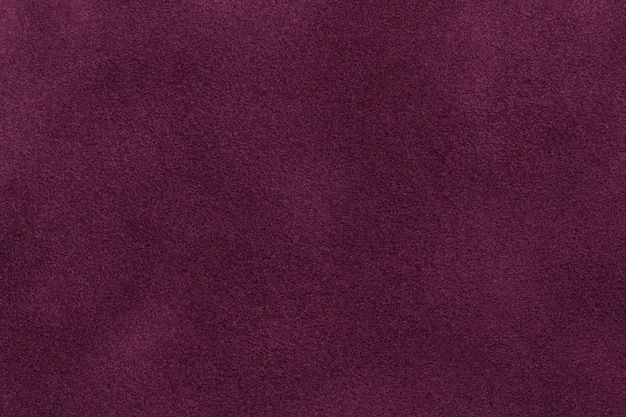 Photo background of dark purple suede fabric closeup. velvet matt texture of wine nubuck textile