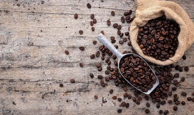 Background of dark roasted coffee beans with scoops setup on wooden background with copy space