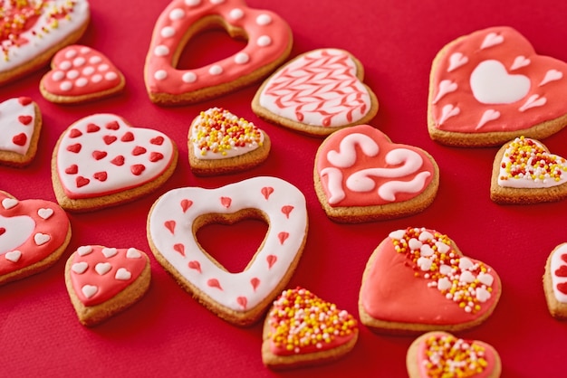 Background of decorated with icing heart shape cookies on red background, flat lay. Valentines Day food concept