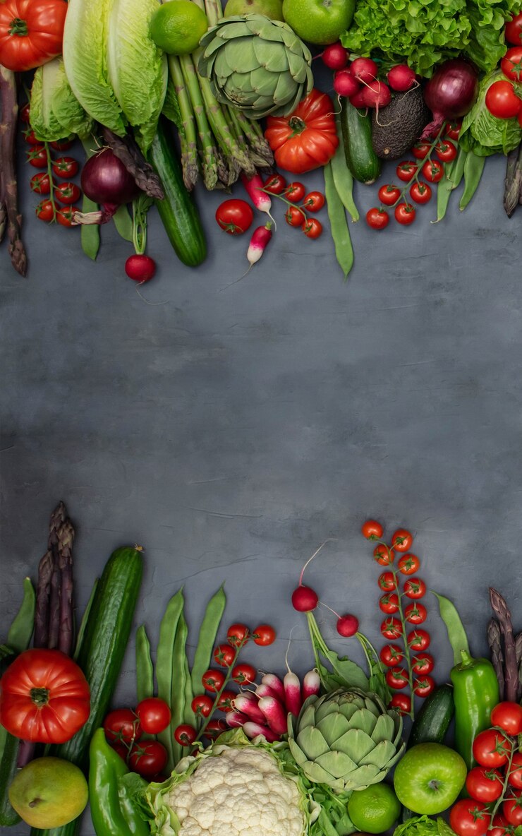 Background of different organic vegetables - asparagus, tomatoes cherry, avocado, artichoke, pepper, lime, redish, cauliflowerm, green beans, cucumber on gray background.