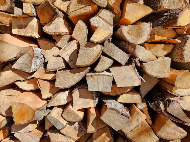 Background of dry chopped firewood logs stacked up on top of each other in a pile.Row of fire wood stock for winter.Selective focus. firewood logs