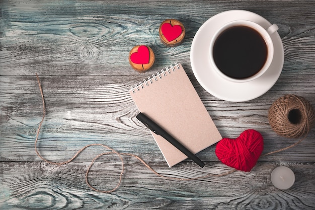 Background for February 14 with coffee, Notepad and hearts on a wooden background.