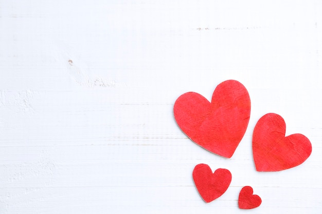 Background of four wooden hearts on an old rustic white table