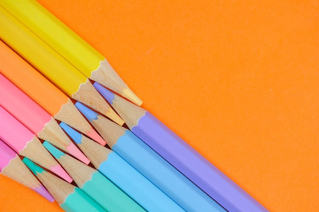 Foto sfondo di matite colorate su carta arancione