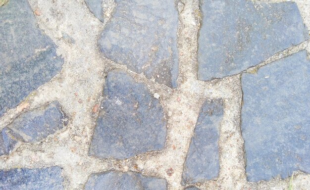 Фон из темно-серой тротуарной плитки различной формы и песка