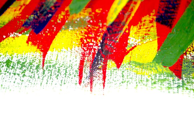 Background from different strokes of red, yellow, green and blue paint with brush on white background close-up. Bright colorful backdrop of brush lines. Mixing color streaks of paint on white canvas