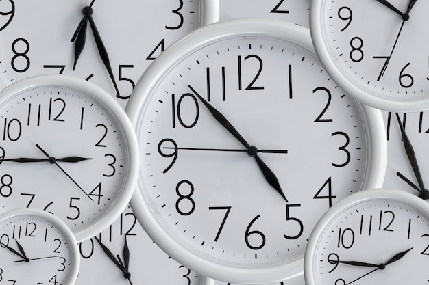 Background from set of white analog round office clocks of different sizes showing various time