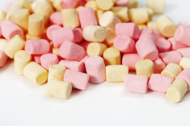 Background from yellow and pink zephyr Small candy marshmallow Sweet food fon with copy space