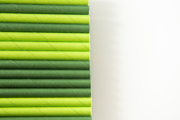 Background of green paper drinking tubes of green color on a white background