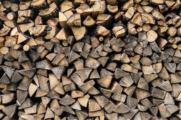 Background of hewed smooth wooden logs. Cut wood texture. Pile of chopped fire wood prepared for winter