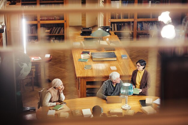 Background image of classic library interior with diverse group of people at table copy space