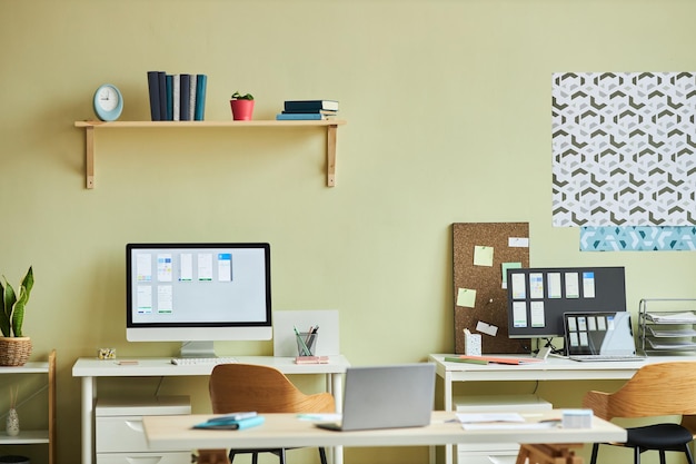 Background image of minimal office interior with computers on desks and pastel yellow wall copy spac